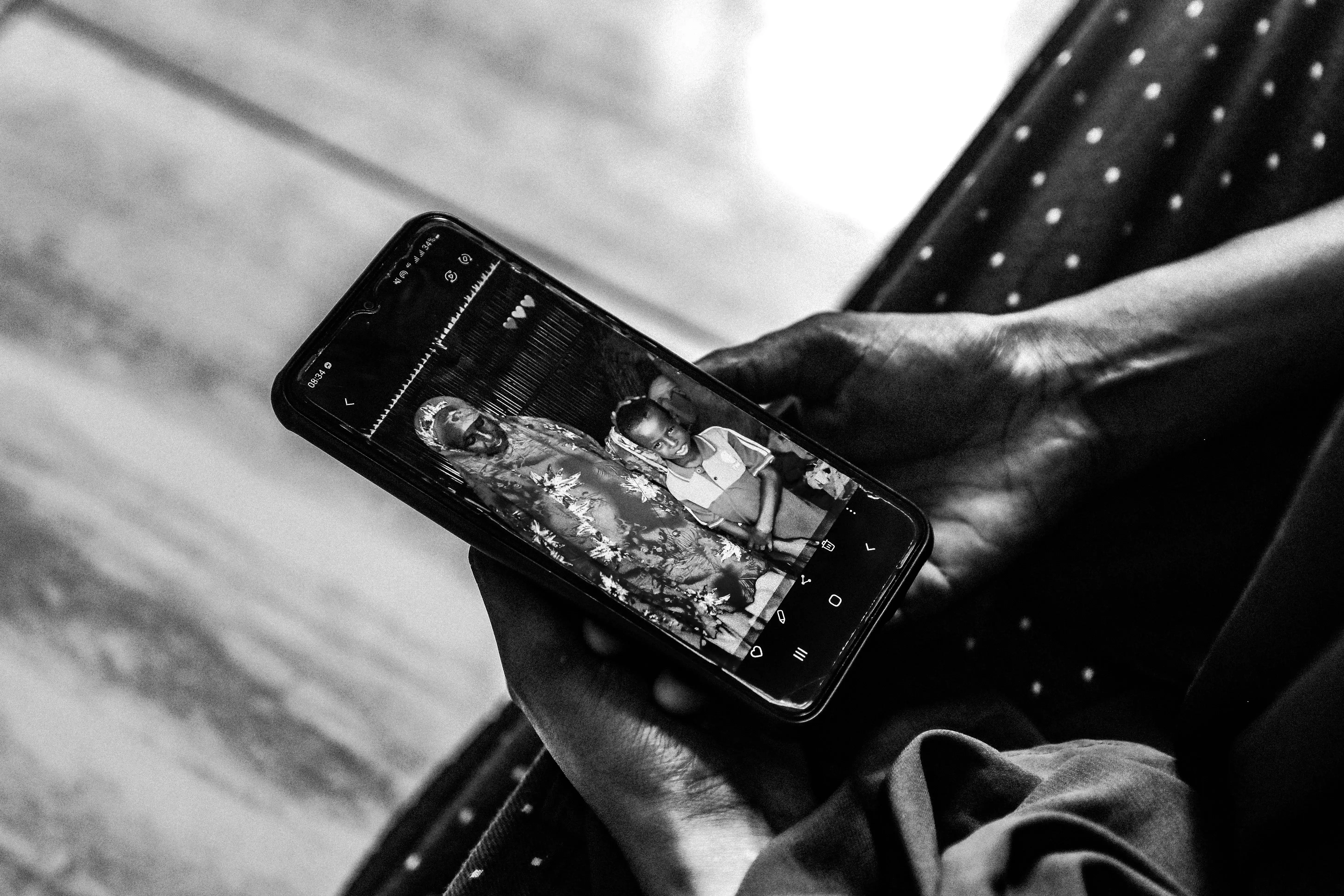 A person holds a phone showing an image of a mother and son. 
