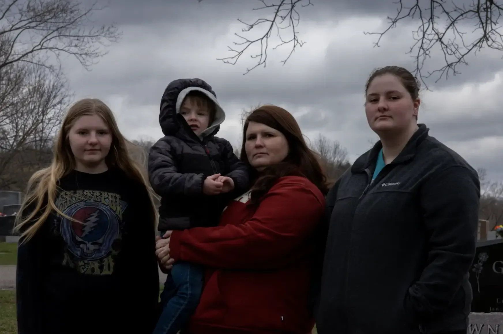 family poses for a portrait next to Rodgers’s gravestone