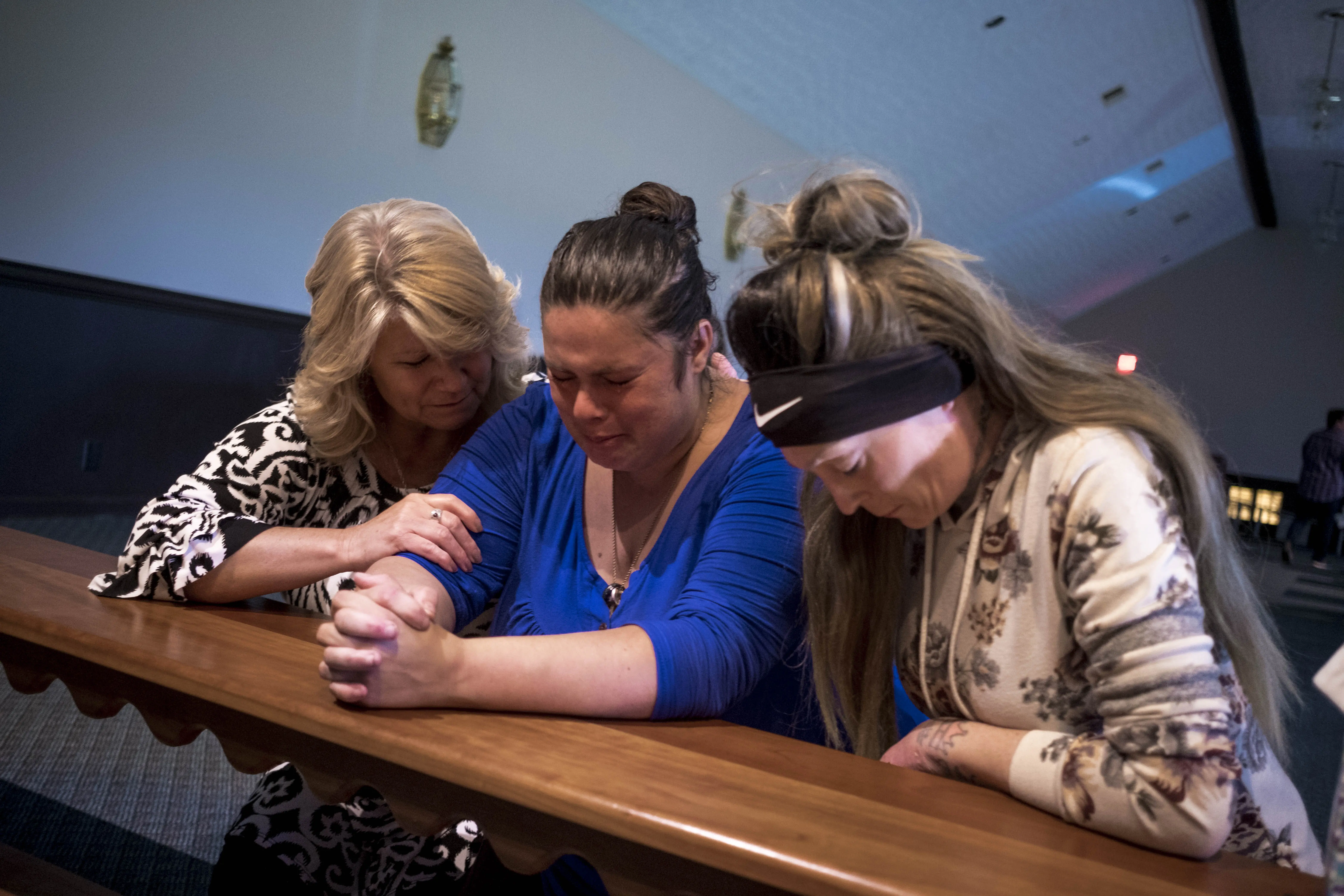 Three women kneel at a church altar.