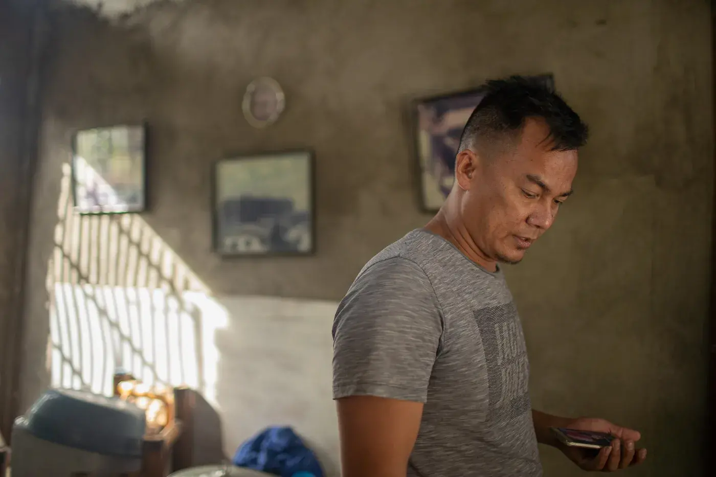 A man, appearing stressed, is at his home and gazes toward the frame's bottom-right