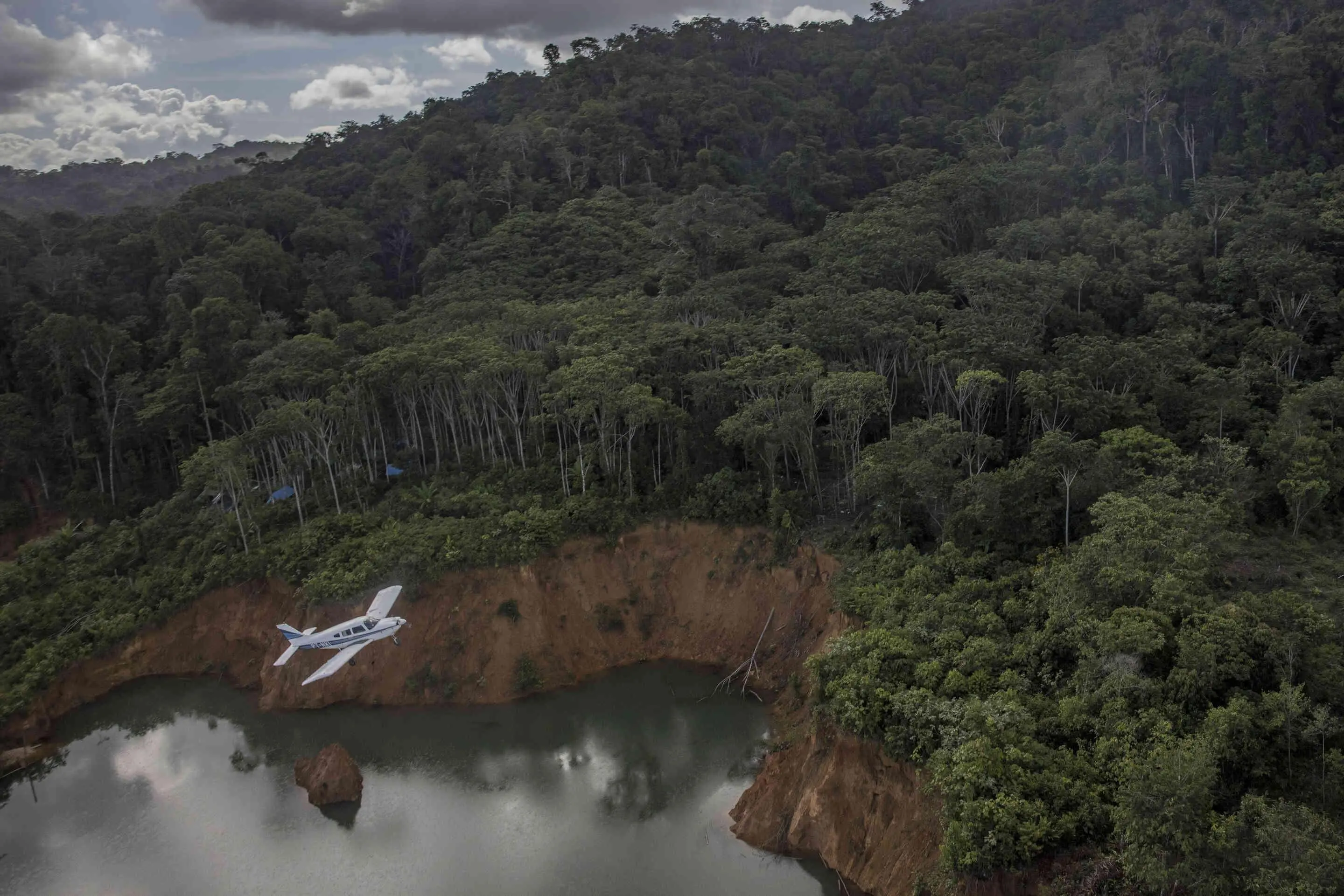 A small plane flies over the rainforest.