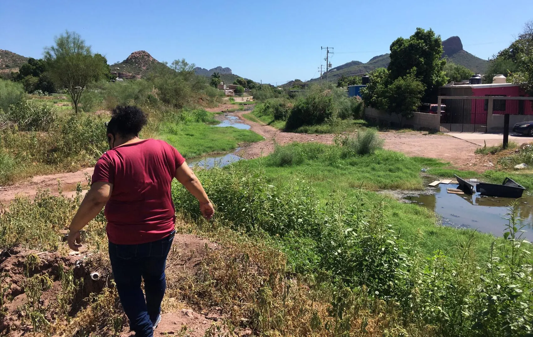 Woman walks next to sewage flowing in the river