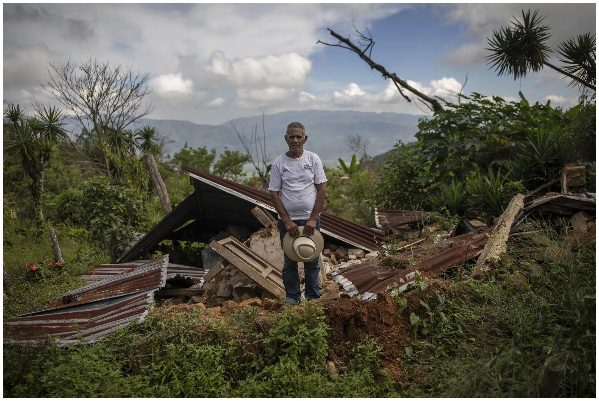 a man stands amongst the ruins of his house