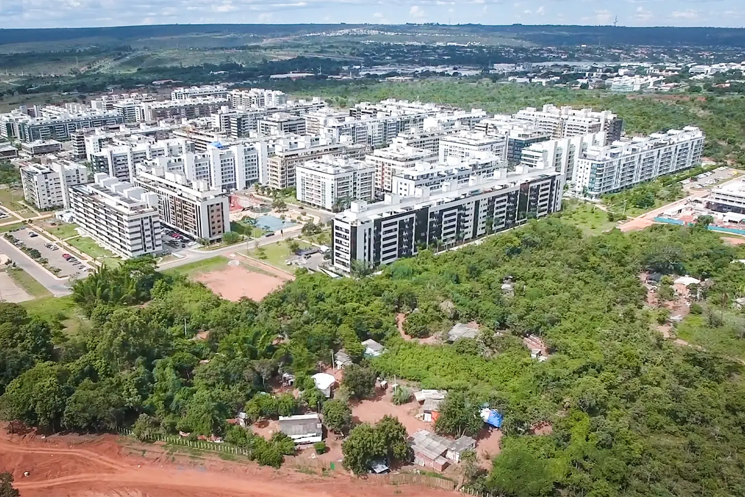 Aerial view of forested area next to apartment buildings.