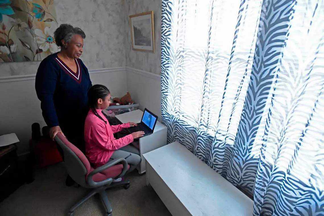 Regina Barrett stands with her granddaughter Hallie Barrett, 10, in the room she used as a remote classroom in ReginaÕs Monroe, NC home on Wednesday, February 10, 2021. Regina Barrett began juggling the roles of grandmother, caregiver and teacher when the pandemic shutdown schools last year. Image by David T. Foster III. Unites States, 2021.