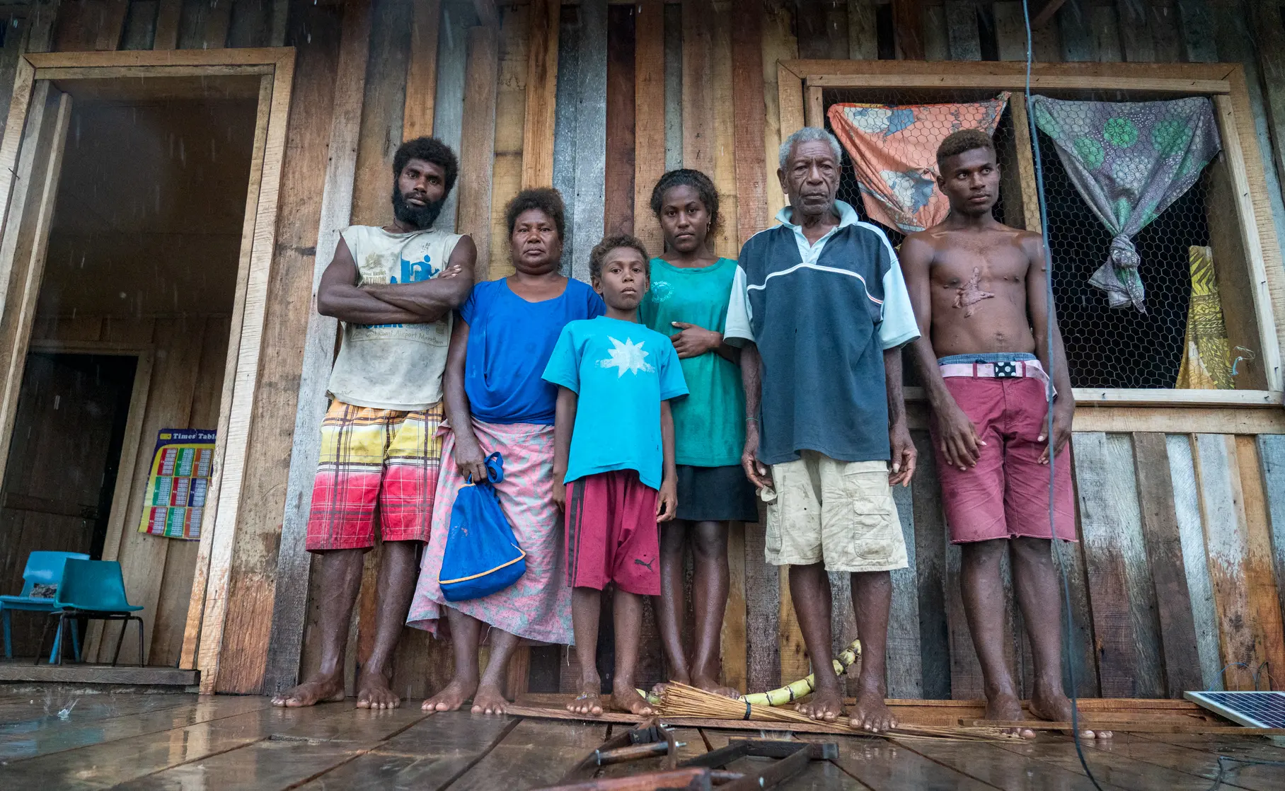A family in the Solomon Islands stand in front of their home