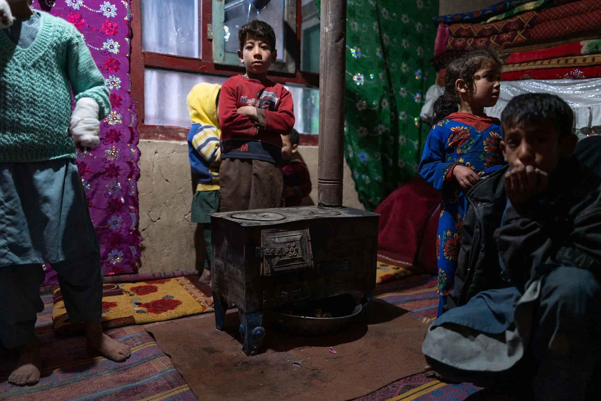 A young  boy stands with other children around stove