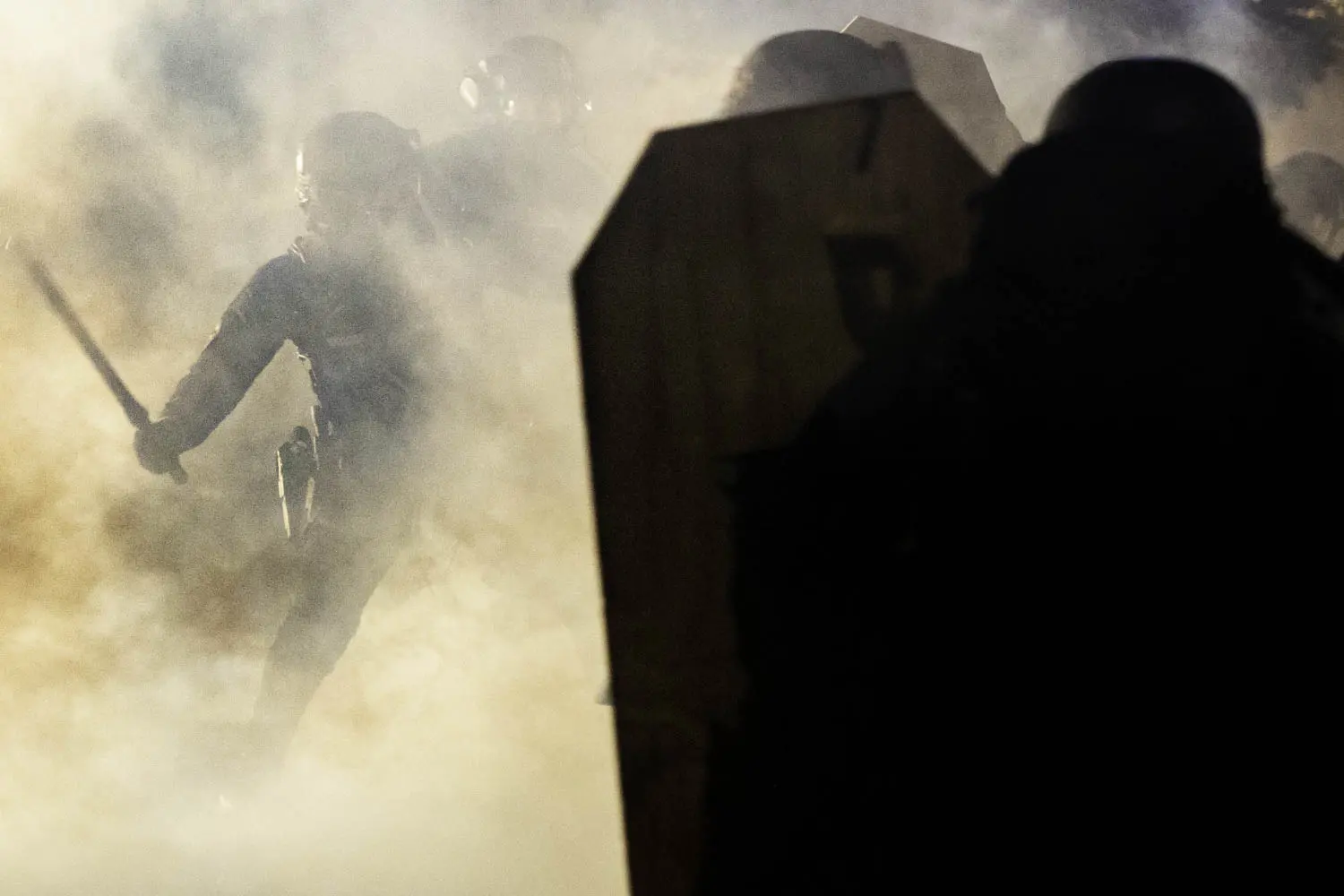 A Portland Police officer wields a billy club against a protester amidst a cloud of teargas<br />
 outside of the North precinct in Portland, Oregon.