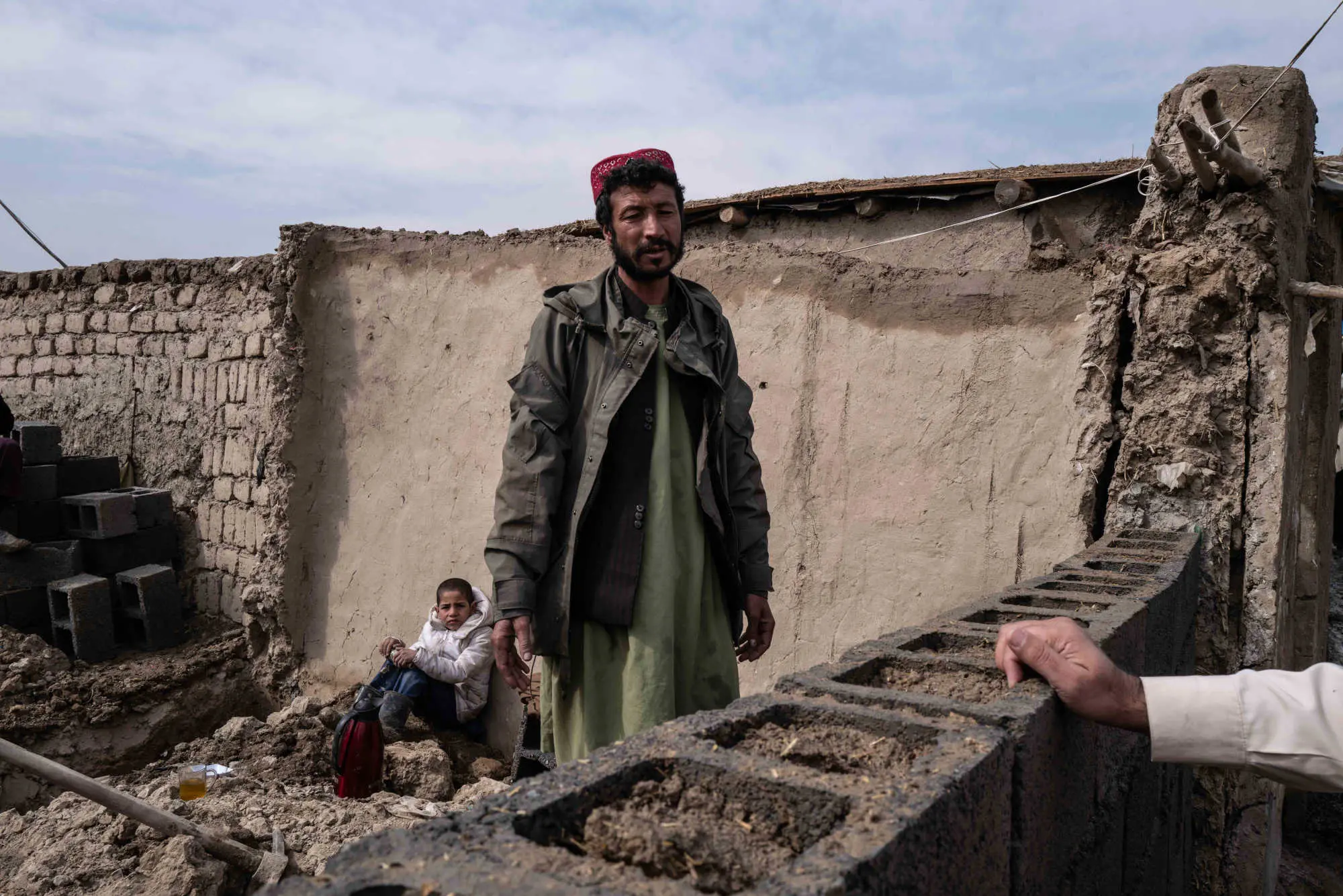 A man stands in front of wall that had collapsed during snow melt