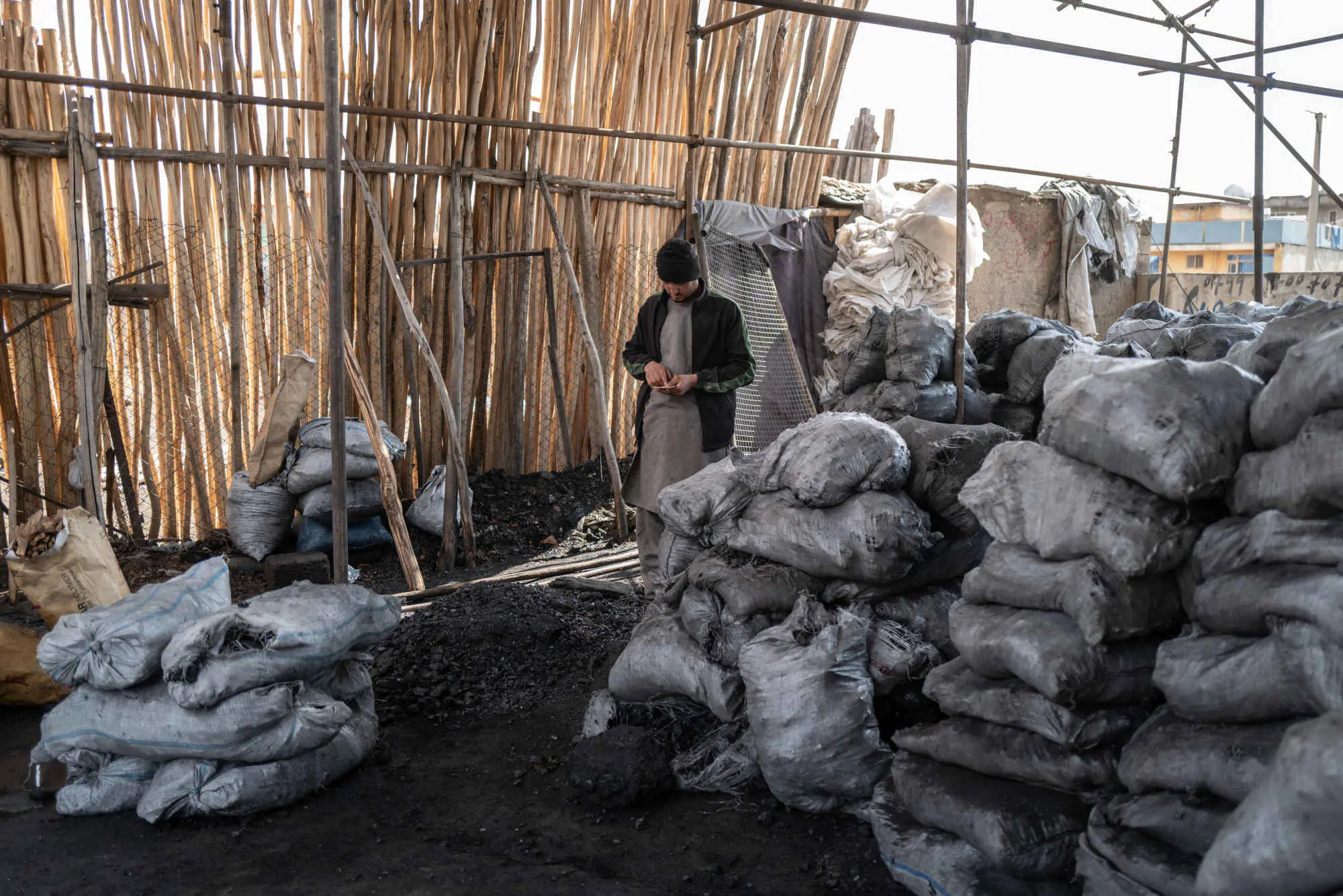 A man standing amongst bags of coals