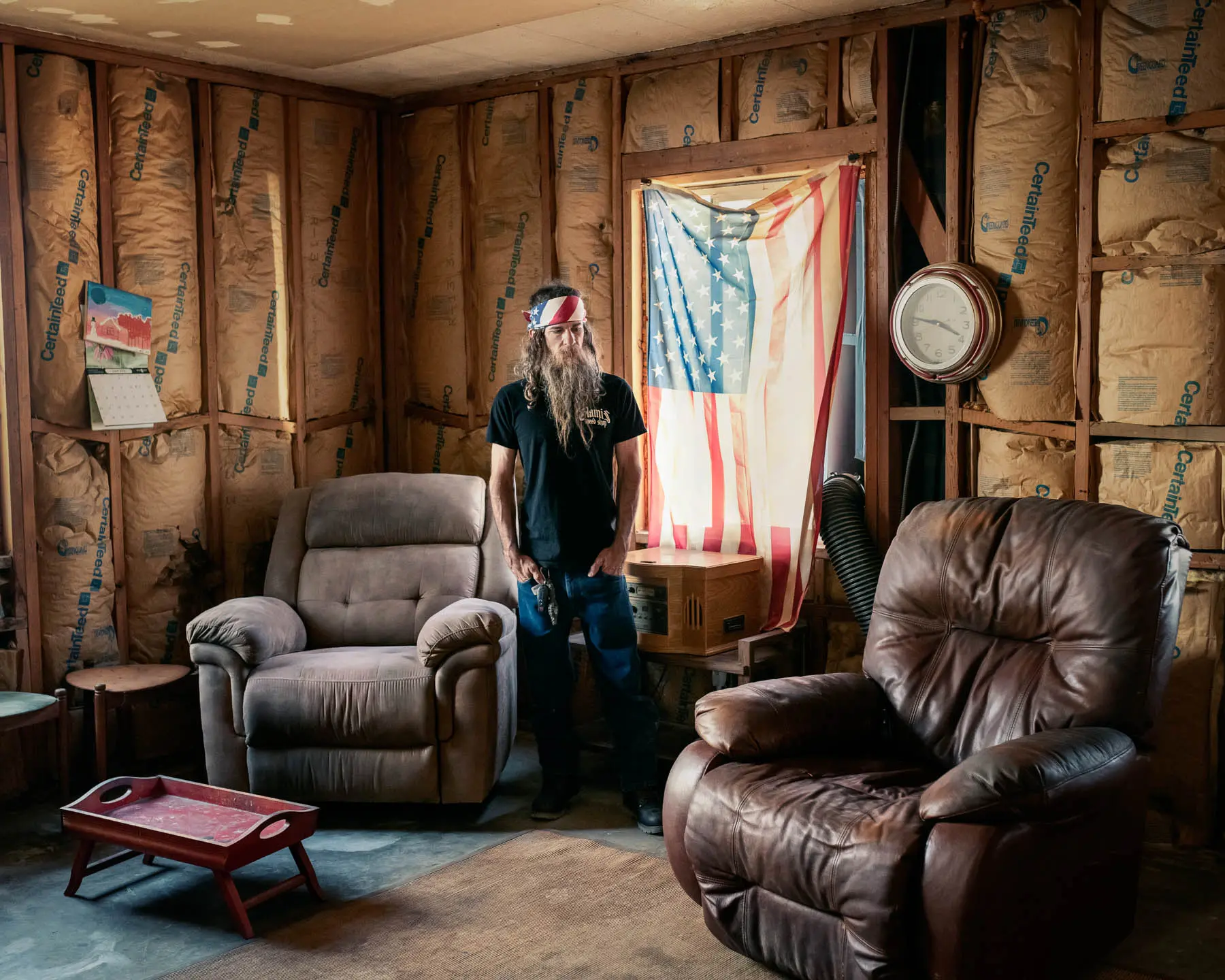 Man stands in his living room with american flag in background