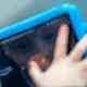 David looks up educational math videos on his iPad. David, who has autism, spends a lot of time using his iPad watching educational math videos. Image by Michael Santiago. United Kingdom, 2019.