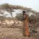 Hades, 16, an Ethiopian Tigray migrant, makes a phone call to her mother in Ethiopia as she takes shelter under trees at the last stop of her journey before leaving by boat to Yemen in the evening, in Obock, Djibouti, July 15, 2019. Hades did not know that there is a civil war in Yemen. She was told by her guide that women are safe in homes of their employers in Saudi Arabia and that she would not face deportation. Image by AP Photo / Nariman El-Mofty. Djibouti, 2019.