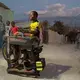 Gemps Rosembert, 31, sharpens knives with a portable machine he has made himself that relies on a pedal driven motorcycle tire to spin the grinding wheel in the Canaan 4 neighborhood. 'I charm my customers with music,' says Rosembert, who is partial to reggae and has named the machine 'File Mix.' He sharpens to a curated musical selection he plays from a boombox. Image by Allison Shelley. Haiti, 2019.