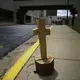 A wooden cross made from a tree stump, known by some locals as a symbol of hope, sits outside of Phoebe Putney Memorial hospital on Monday, April 20, 2020, in Albany, Ga. The patients were very sick. Some died within hours. Some died on the way, in the back of ambulances. The region is predominantly black, but even so, African Americans died disproportionally, said Phoebe Putney Memorial's chief executive officer Scott Steiner. Image by Brynn Anderson / AP Photo. United States, 2020.