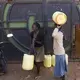 Women carrying containers walk to a merchant who sells drinking water in the Kawangware slum in Nairobi, Kenya. Many of Nairobi's people live in slums and have limited access to clean drinking water and proper sanitation. Image by Mark Hoffman. Kenya, 2017. 