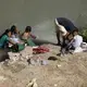 Migrants swim and wash clothes in the Rio Grande under the Gateway International Bridge in Matamoros. Image by Miguel Gutierrez Jr. Mexico, 2019.