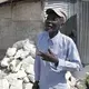 Telfort Innocent, 67, stands in front of his tin shack inside the Teren Toto camp in Delmas, Haiti. Image by Jose A. Iglesias. Haiti, 2019.