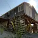 A storm-damaged, uninhabitable home sat on stilts on Salt Marsh Road on Spring Hill beach. Image by John Tlumacki. United States, 2019.