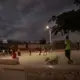 Young men exercise after dark in the recently completed public plaza in the Canaan 1 neighborhood. The community fought hard to keep the land a park after a Haitian man living in Miami tried to claim it as his own, surrounding it with fencing in preparation for building a private home. The park improvements, funded in part by by the American Red Cross, include solar-powered lights. Image by Allison Shelley. Haiti, 2019.