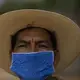 Jorge Vazquez wears a face mask amid the spread of COVID-19 outside his home in San Jeronimo Xayacatlan, a town in Mexico from where nearly a third have emigrated to New York, Wednesday, June 24, 2020. Trained as a nurse, the 42-year-old has returned home for good from New York where he emigrated twice. Image by Fernando Llano/AP Photo. Mexico, 2020.
