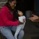 Nataly Ortega, whose mother Magnolia Ortega works cleaning homes in Staten Island, New York, holds her niece Azul in San Jeronimo Xayacatlan, Mexico, Wednesday, June 24, 2020. Nataly's uncle recently had a telephone installed so they can stay in touch with Nataly's mother, whose cancer is in remission, but remains vulnerable to COVID-19. Image by Fernando Llano/AP Photo. Mexico, 2020.