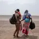 In this July 23, 2019 photo, Fatma and her husband Yacoub, migrants from Mali, carry their children as they make their way in Lahj, Yemen. Mohammed, traveled with her husband, a construction worker, and two children, through Djibouti on their way to Saudi. Once they reached the shore, they were held for several days by traffickers. Image by Nariman El-Mofty / AP Photo. Yemen, 2019.