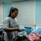 Lady Eleponga, a midwife working under a 3-month contract who is now working to prevent the spread of the virus, prepares her cloth mask by using tissue paper as an added protection. Image by Xyza Bacani. Philippines, 2020.
